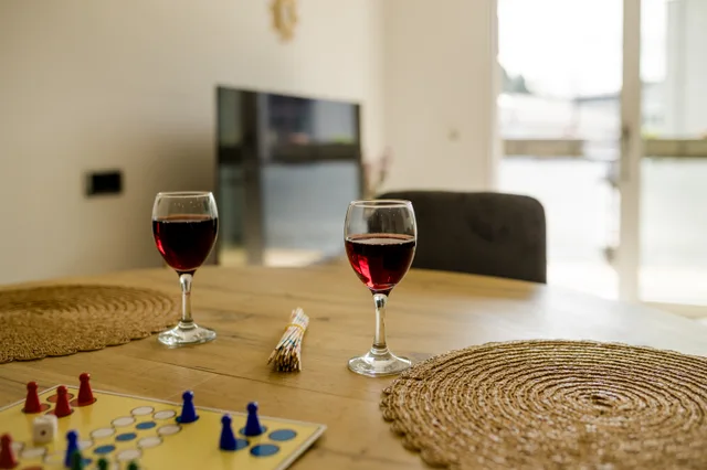 Gedeckter Esstisch mit Weingläsern und Brettspiel.
