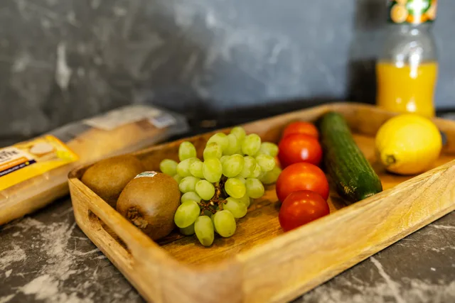Obst und Gemüse auf einem Holztablett auf der Küchenarbeitsfläche.