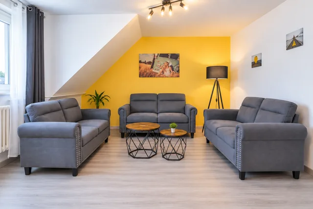 Drei graue Sofas mit runden Couchtischen im Wohnzimmer.