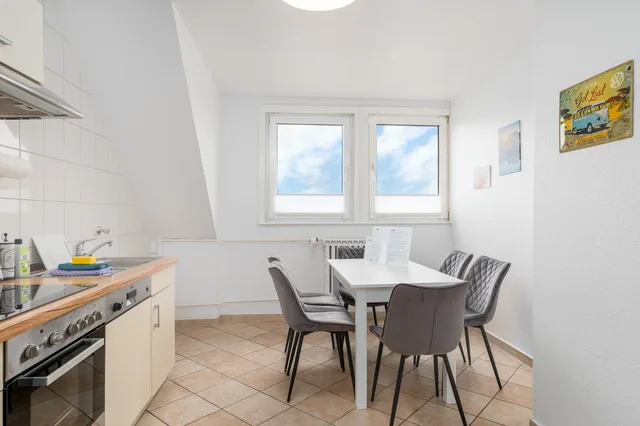Esstisch mit grauen Polsterstühlen neben dem Küchenfenster.